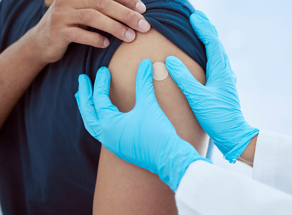 Healthcare professional administering a Band Aid after a tetanus shot to an adult worker